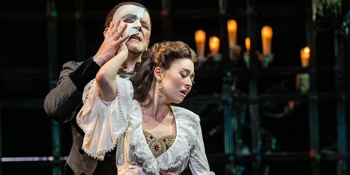 Anna Zavelson as Christine and Dean Chisnall as The Phantom, performing on a dimly lit stage.