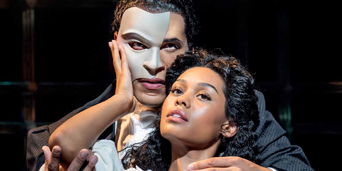 Jordan Donica, wearing a mask, embraces Beatrice Penny Touré, both gazing intensely at the camera.