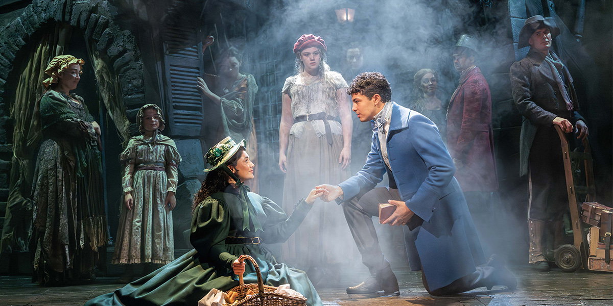 A scene from Les Misérables featuring actors in period costumes, with dramatic lighting and a dark, moody background.