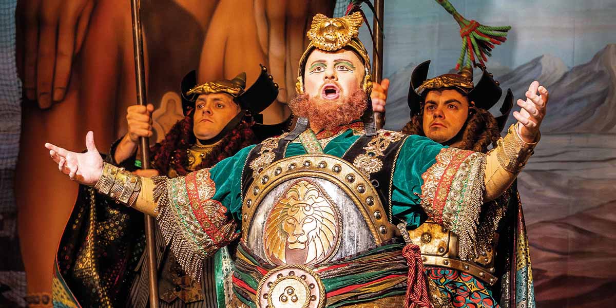 Matt Bateman as Ubaldo Piangi, wearing a costume with rich textures, performing on stage with dramatic lighting.