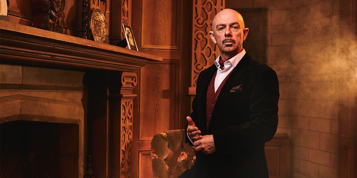 A scene from "The Mousetrap" featuring actors in period costumes on stage, with dramatic lighting.