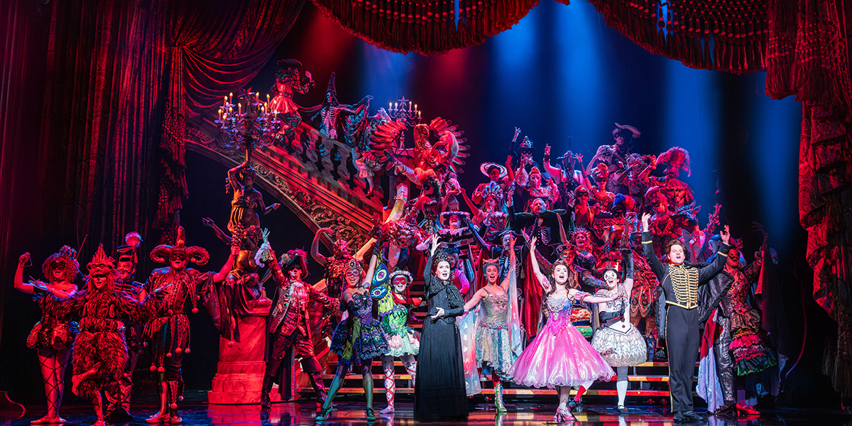 A dramatic scene from "The Phantom of the Opera," featuring a masked figure in a dark, ornate setting.