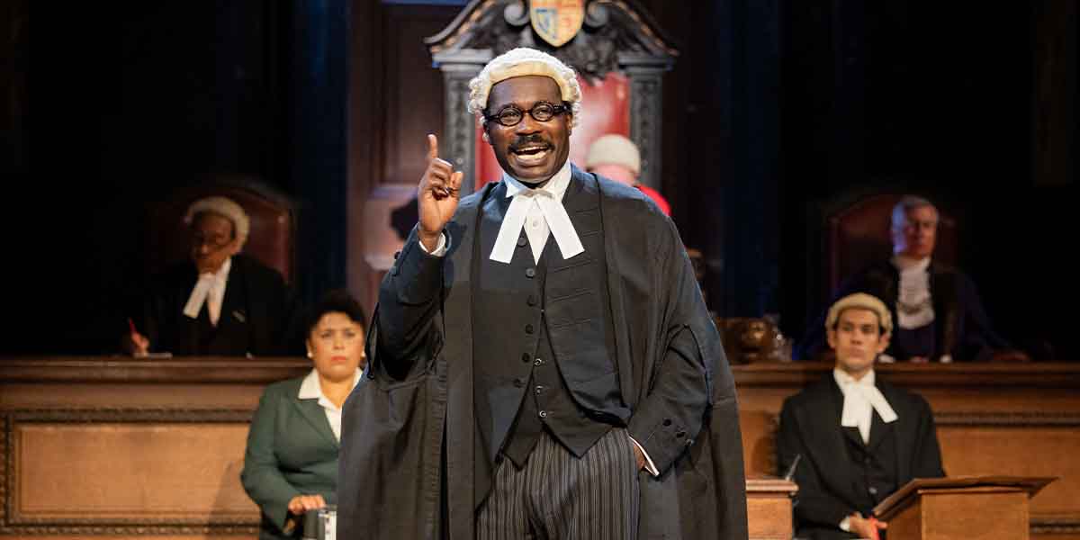 Jude Owusu, dressed in a black gown and wig, gestures while speaking in a courtroom setting.