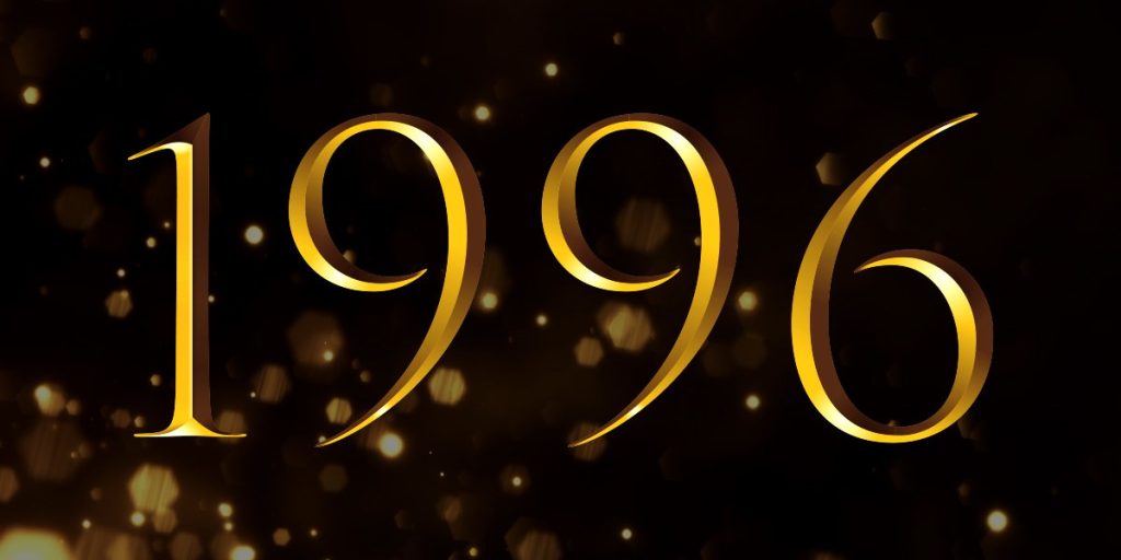 A group of elegantly dressed individuals celebrating at an awards ceremony, with a stage and audience in the background.