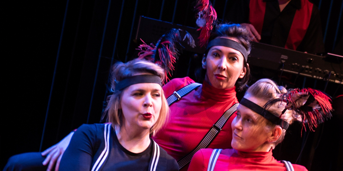 A group of performers in vibrant costumes energetically engage in a musical performance on stage.