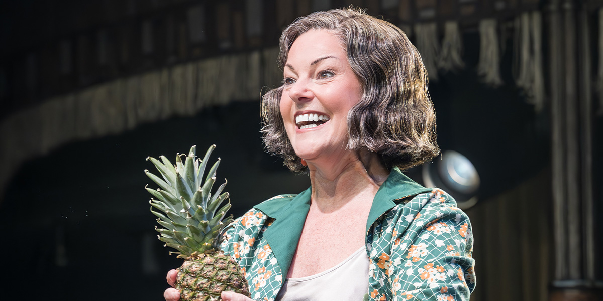 A performer in a sequined costume poses dramatically on stage, with vibrant stage lights illuminating the scene.