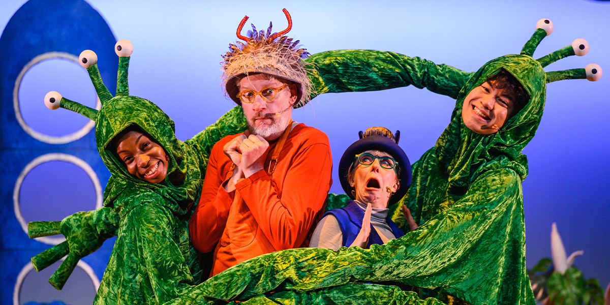 Four performers dressed as whimsical sea creatures, with one wearing an ornate crown, on a stage set to evoke an underwater ambiance.