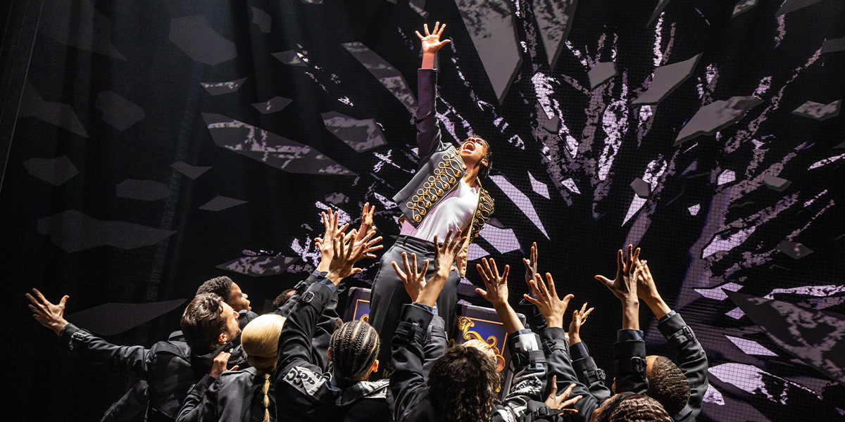 A vibrant stage scene from "MJ The Musical," featuring performers in dynamic dance poses and colourful costumes.