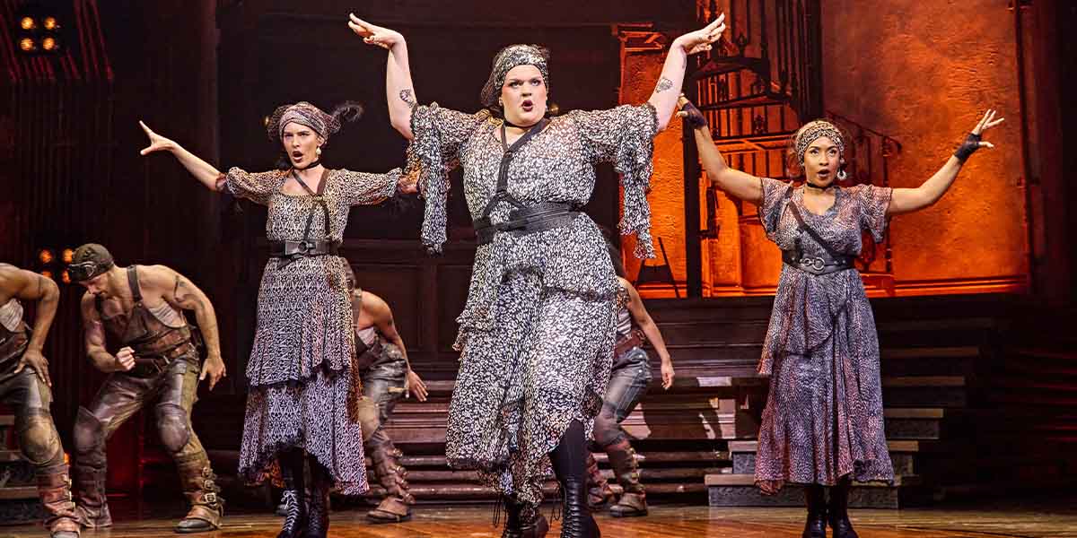 Melanie Bright, Spike Maxwell, and Lauran Rae perform on stage in Hadestown, featuring dramatic lighting and costumes.