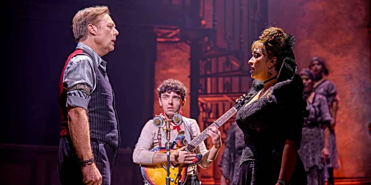 Shaun Dooley and Danielle de Niese perform in Hadestown, with Nathan Sykes playing guitar in the background.