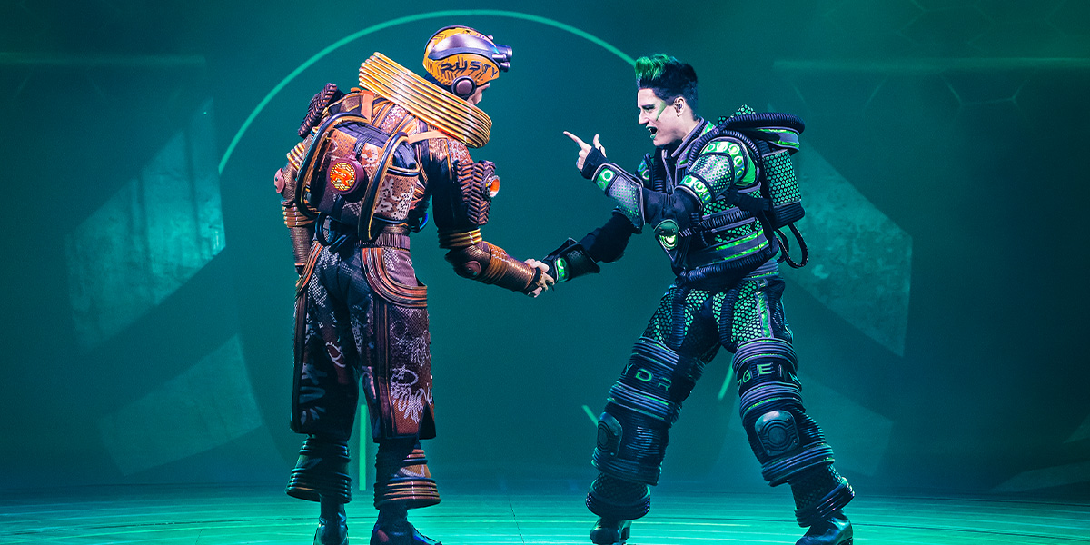 A brightly lit stage with performers in vibrant costumes, showcasing dynamic poses and expressive movements.