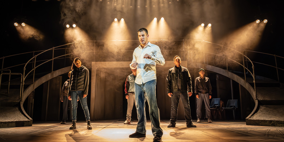 David Shields and the cast of Punch pose together, smiling, in a brightly lit theatre setting.