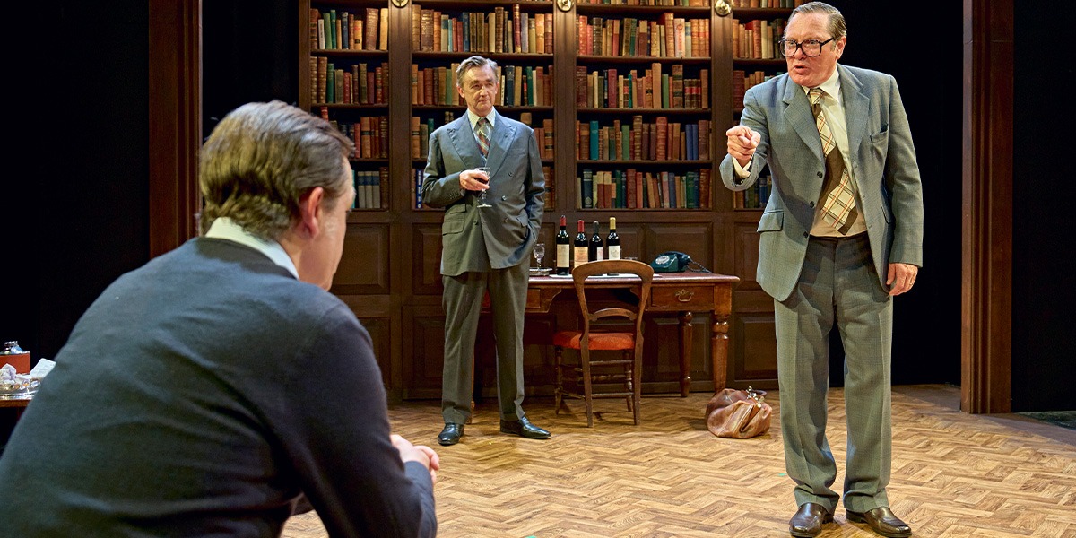 Alan Cox (Tony Crosland) Hywel Morgan (Roy Jenkins ) and Colin Tierney (Denis Healey) are sitting in an office. In the background a large, full bookcase can be seen.