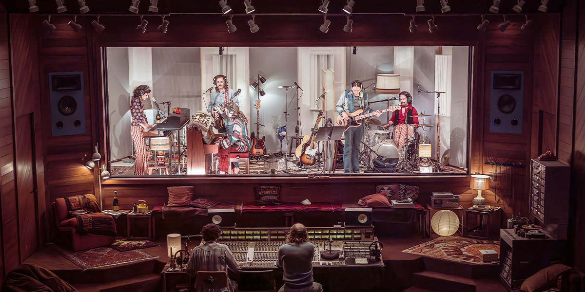 A musician plays a guitar on stage, surrounded by colourful lights and an enthusiastic audience.