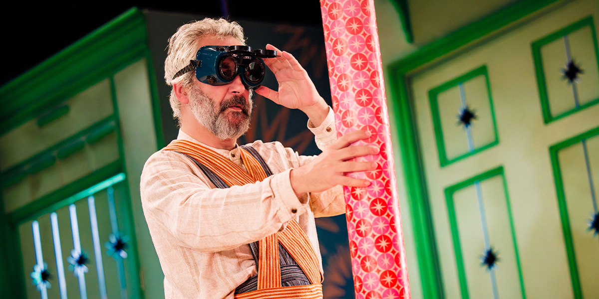 A person stands beside a large, colourful firework , smiling.