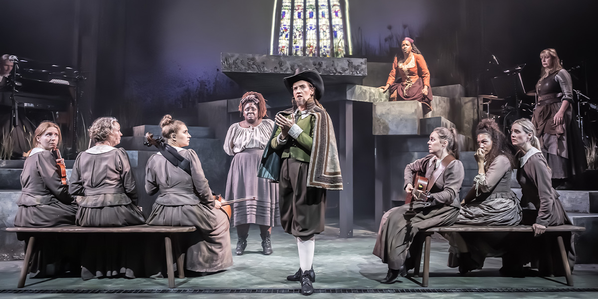 The cast of "Coven" poses together on stage, dressed in varied costumes, with a dark backdrop.