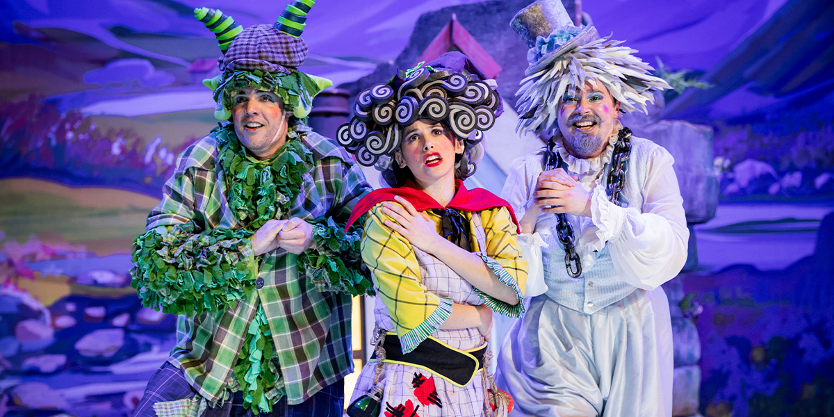 Three characters in vibrant and whimsical costumes on stage.