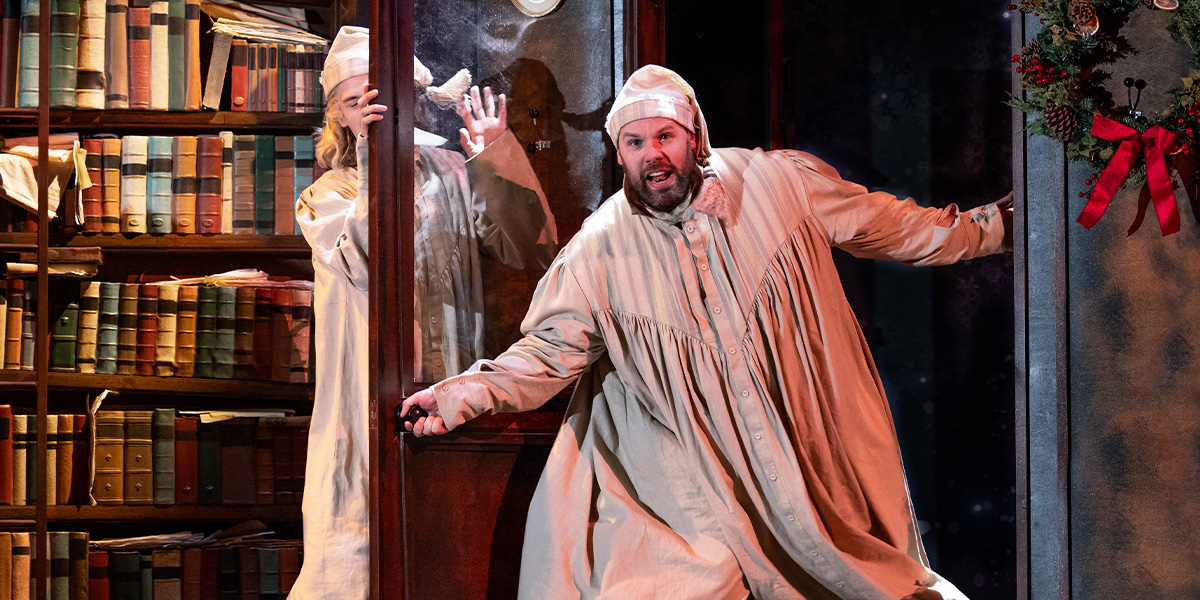 Daniel Fraser and Henry Lewis performing in a scene from "Christmas Carol Goes Wrong," dressed in Victorian costumes.
