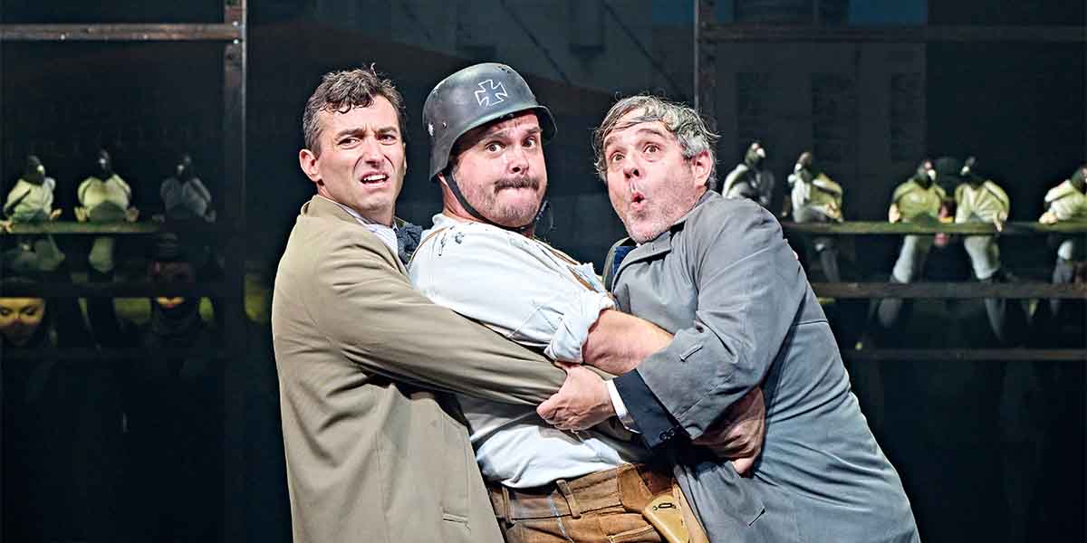 Marc Antolin, Harry Morrison, and Andy Nyman perform a comedic scene, expressing surprise and tension.