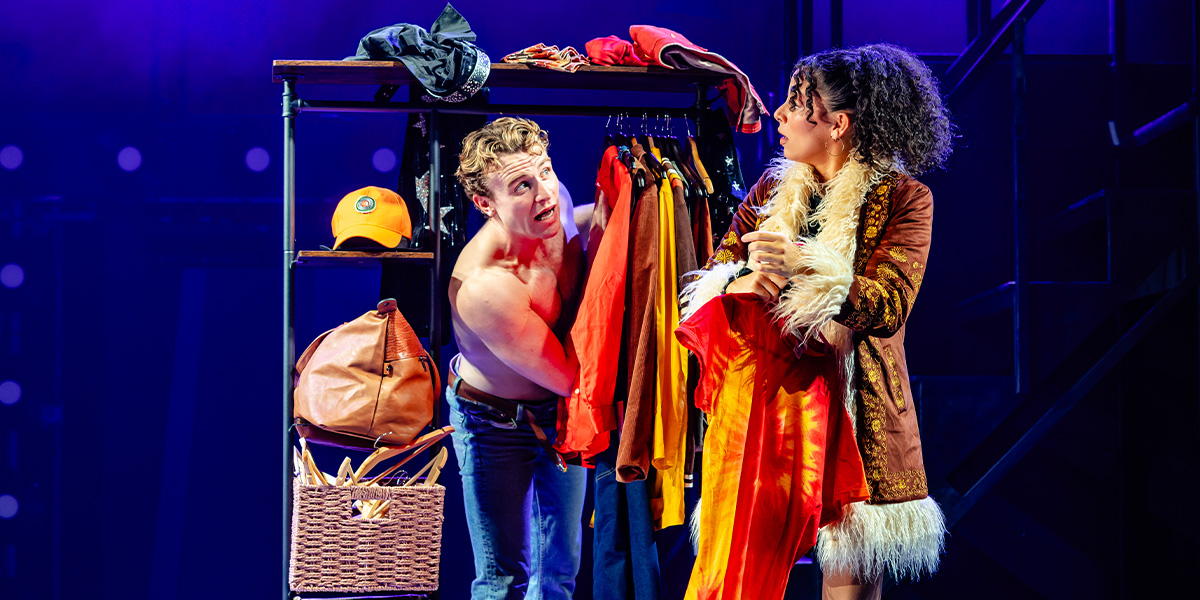 A group of three dancers in vibrant costumes performs energetically on a brightly lit stage.