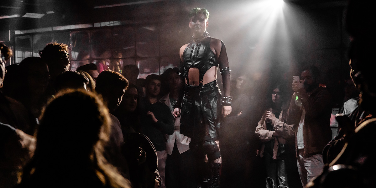 Jan Sport, dressed as Oscar Wilde, poses dramatically in a lavishly decorated room with rich colours.