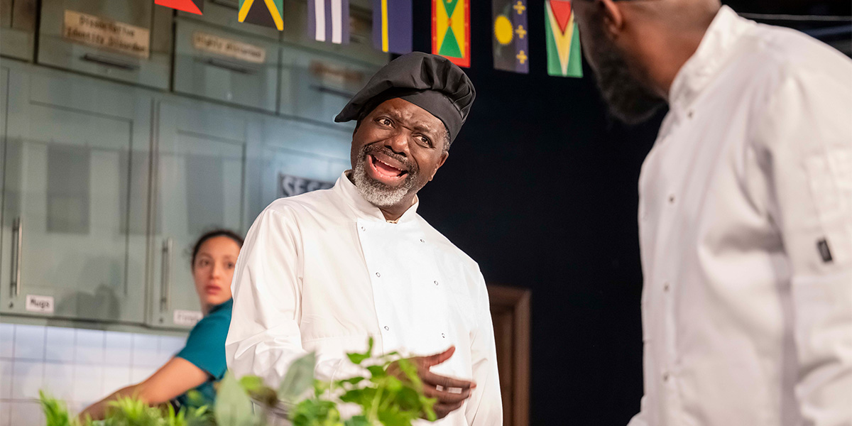 Aimee Powell and Naomi David Webber sit at a table, engaged in conversation, with warm lighting around them.