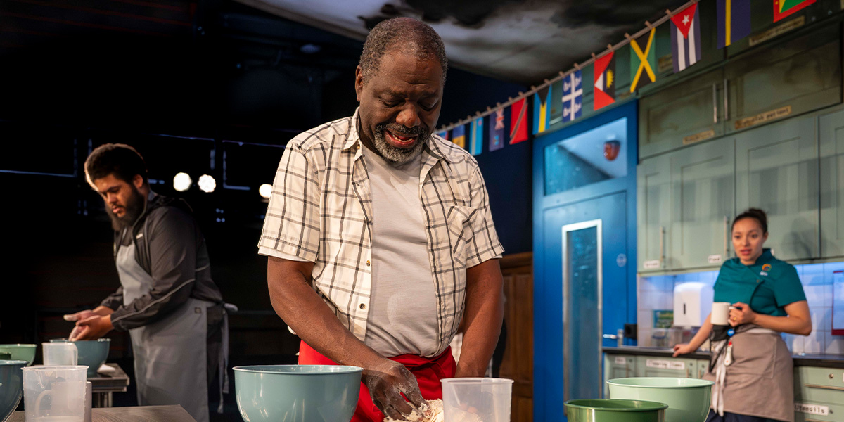 Five people sit together on a sofa, smiling and engaging in conversation, surrounded by warm, neutral decor.
