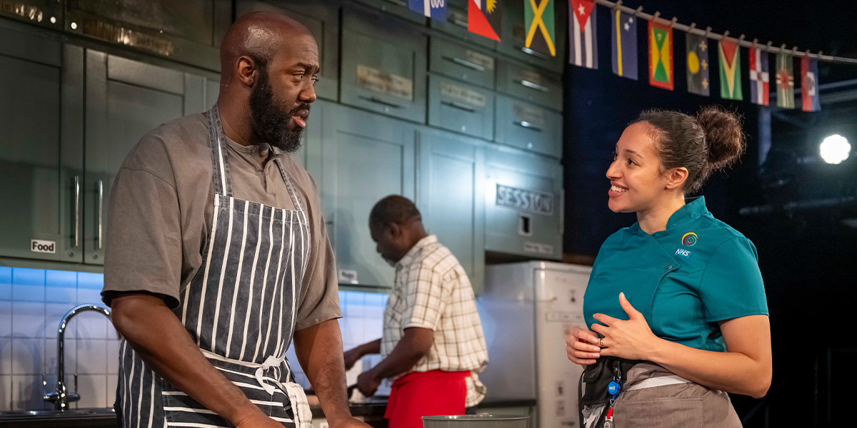 Four individuals stand together, smiling, in a well-lit room with neutral walls and soft furnishings.
