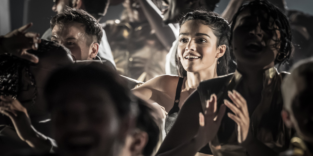 a person smiling brightly at the forefront of a crowd