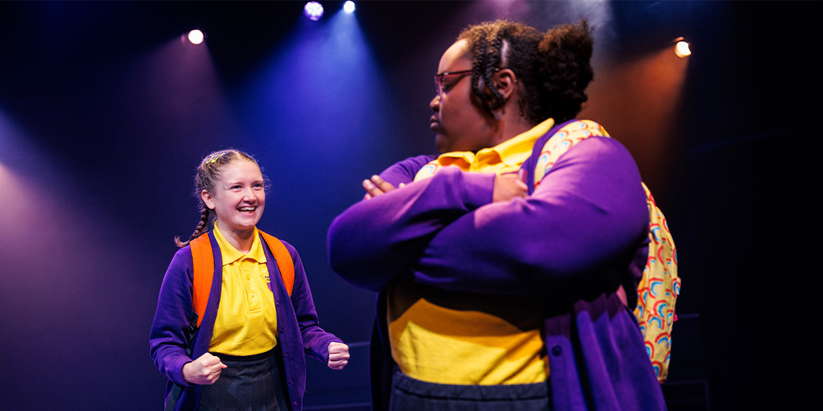 A vibrant cartoon character with oversized glasses and a cheerful expression stands against a colourful, abstract background.