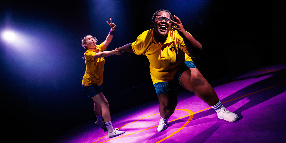 A group of four people, smiling and posing together, wearing colourful casual clothing against a bright backdrop.