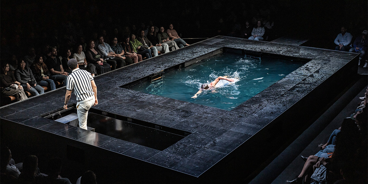 John Macmillan and Andrew Lincoln in theatrical costumes, standing on a stage with dramatic lighting and a dark backdrop.