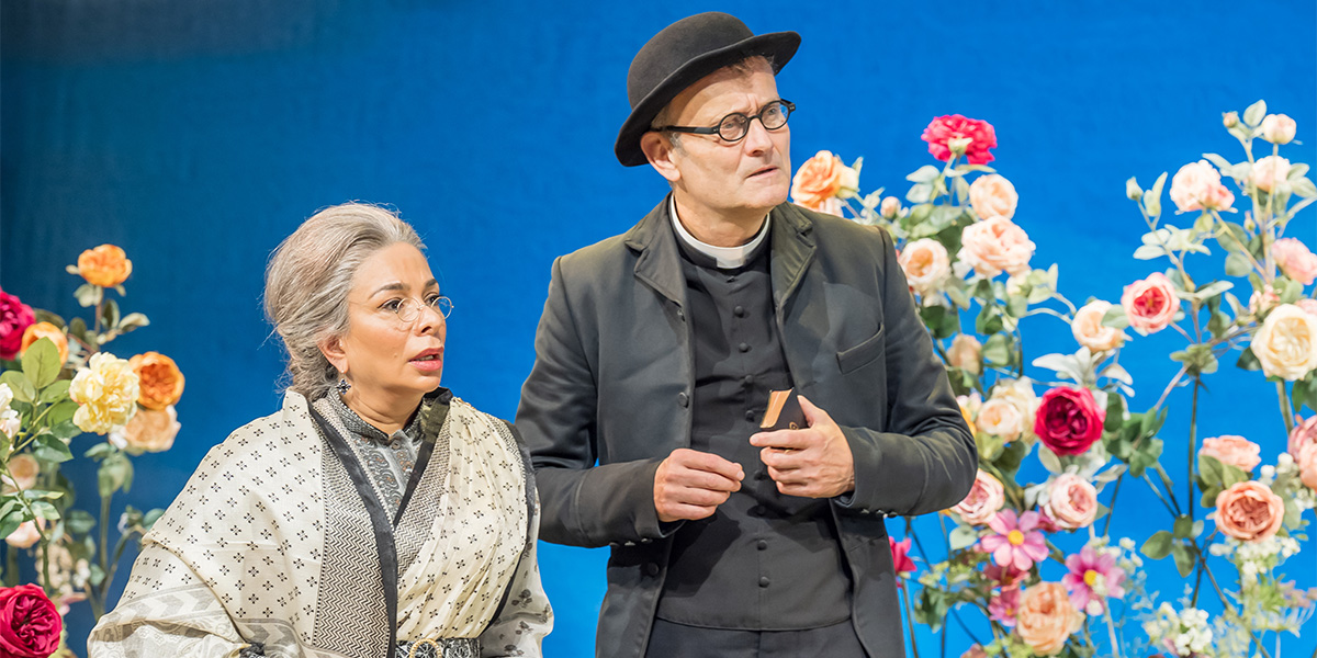 Shobna Gulati and Hugh Dennis pose together, smiling, in formal attire against a theatre backdrop.