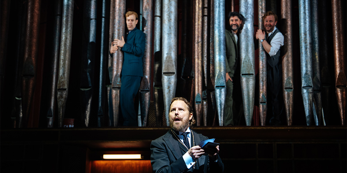 A scene from Twelfth Night featuring actors in period costumes on a stage with elaborate set design.