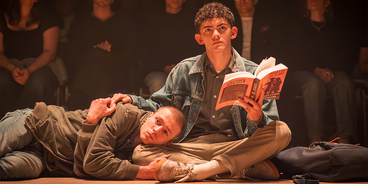 A group of diverse individuals stands together outdoors, smiling, with greenery and a clear blue sky in the background.