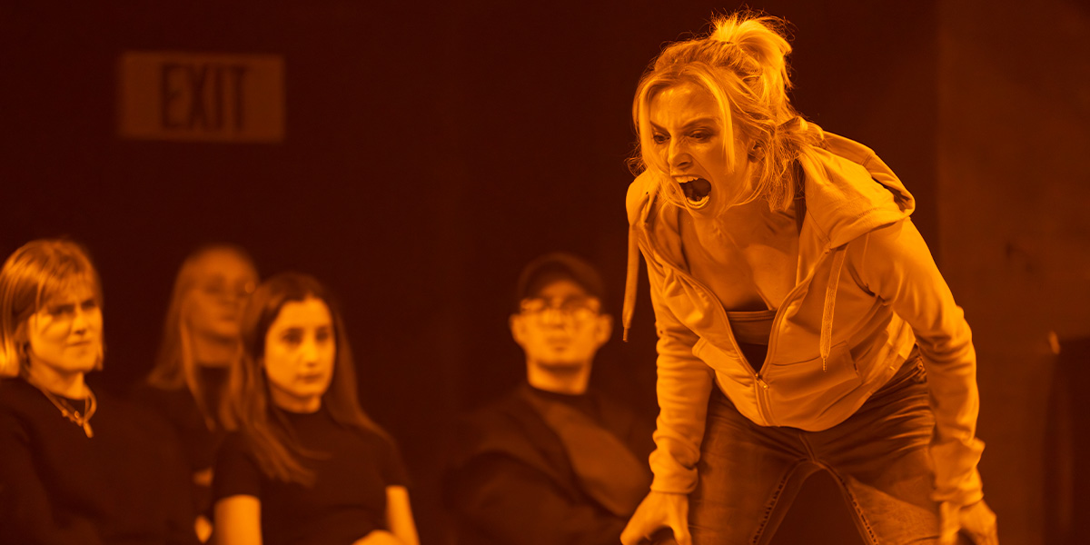 A group of people in formal attire stands together, smiling, with a blurred outdoor background.