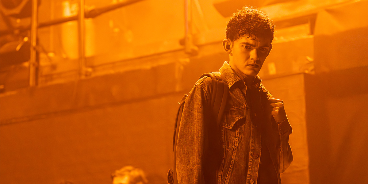 A group of people sit at a table, engaged in discussion, with notebooks and drinks in front of them.