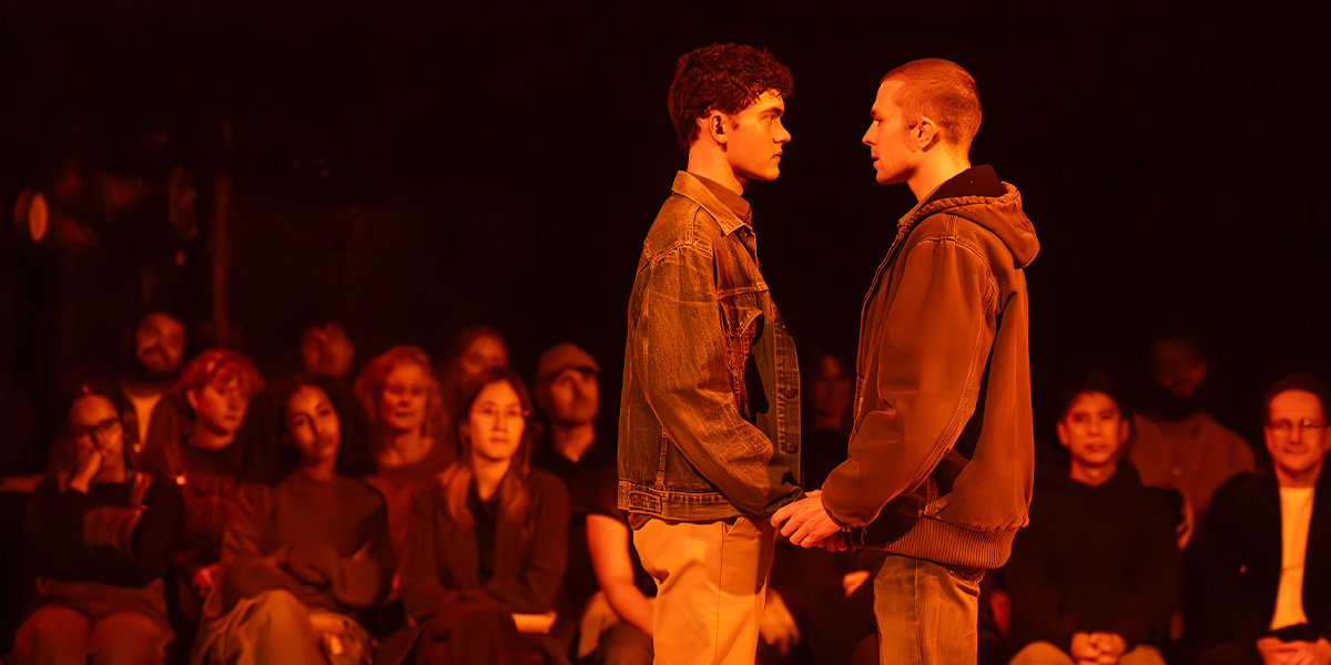A group of people sit at a table, engaged in discussion, surrounded by books and papers.