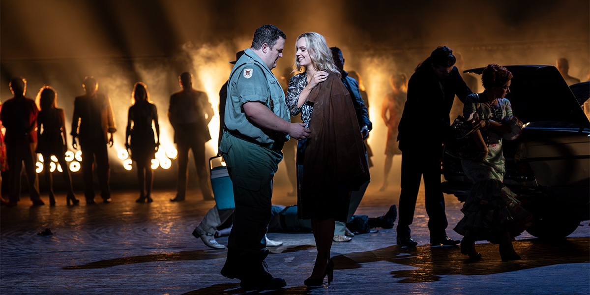 John Findon and Niamh O'Sullivan perform on stage in vibrant costumes, with dramatic lighting and a dark background.