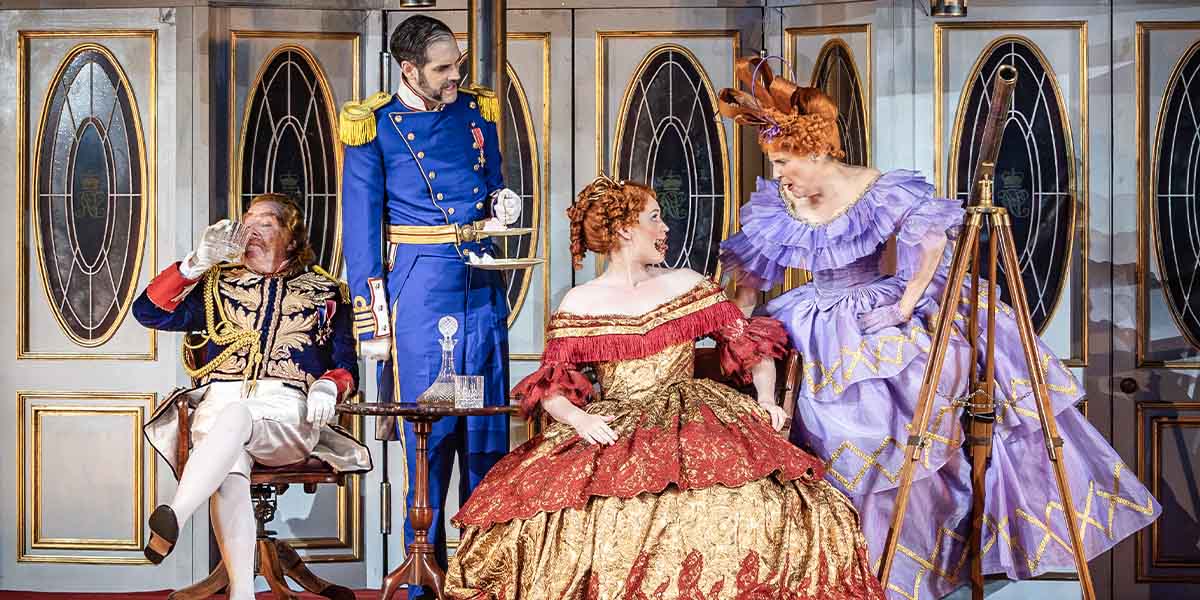 Neal Davies, John Savournin, Bethan Langford, and Mel Giedroyc pose together, smiling, in theatrical costumes.
