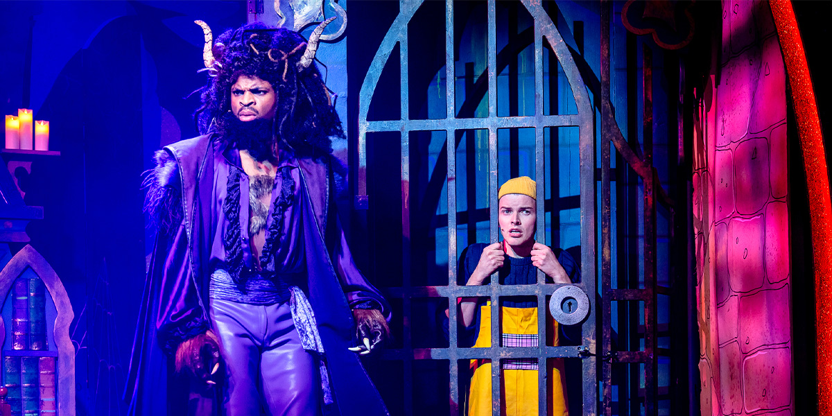 Keanu Adolphus Johnson and Matt Kennedy pose together, both dressed in costume, with a theatrical backdrop.
