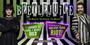 Lydia from Beetlejuice The Musical stands in a dramatic pose, wearing a black dress with red accents.