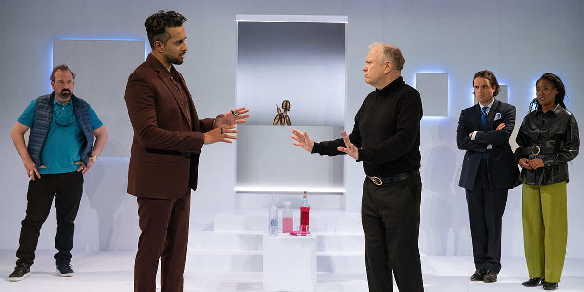 Teddy Cavendish in a dark suit, smiling, with a textured backdrop of soft, muted colours.