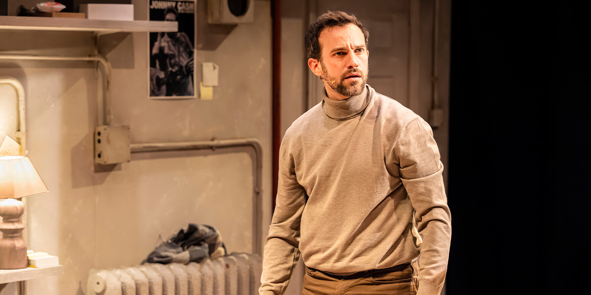 Iffy Mizrahi poses confidently, wearing a stylish outfit, against a neutral backdrop in a professional photoshoot.