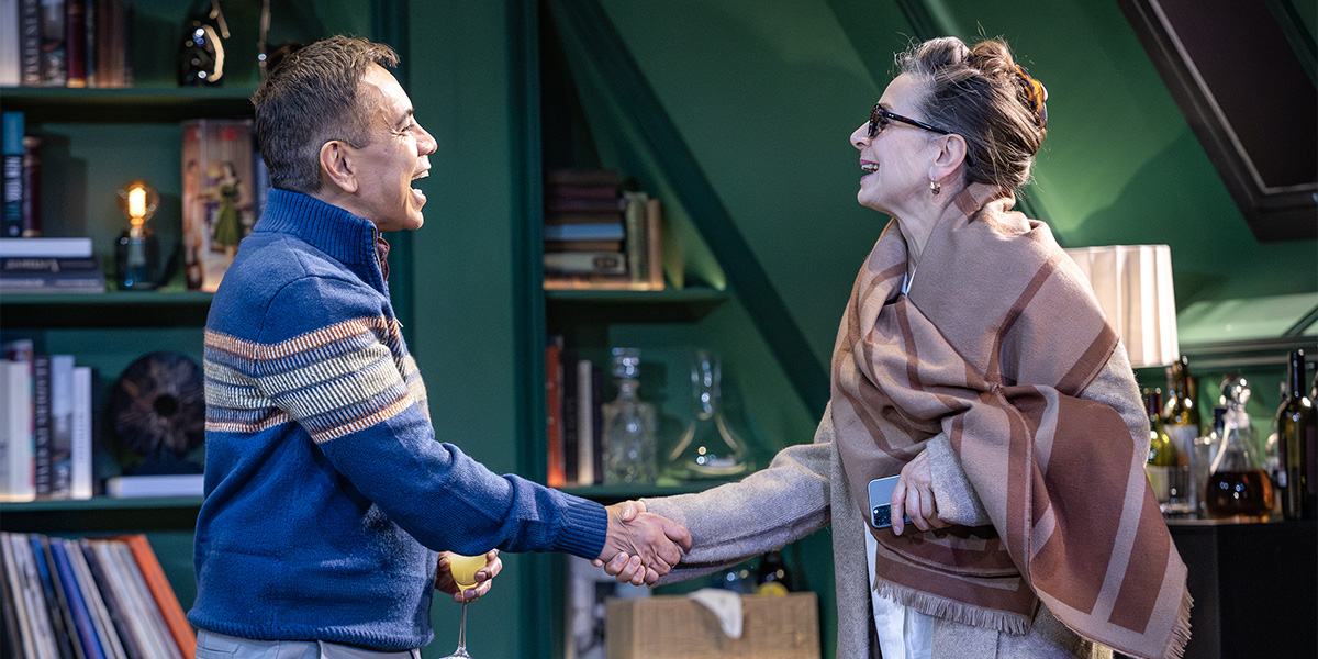 Two people shake hands. They appear to be happy.