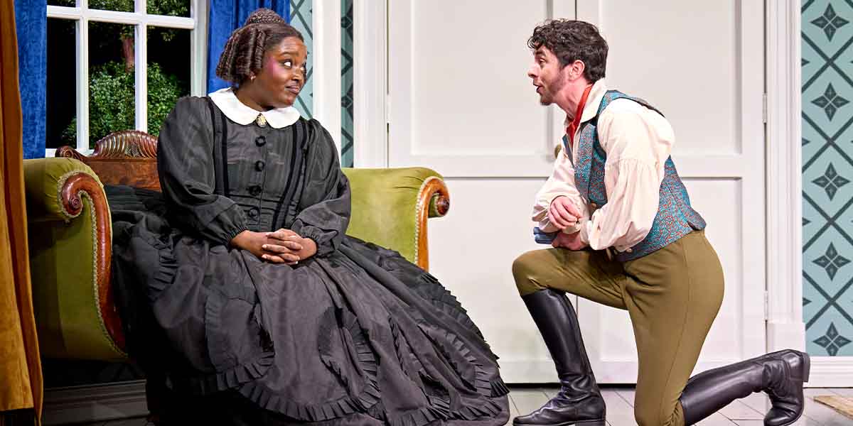 Lolly Adefope as Mary Todd Lincoln sits on a green sofa, while Vinnie Heaven kneels beside her.
