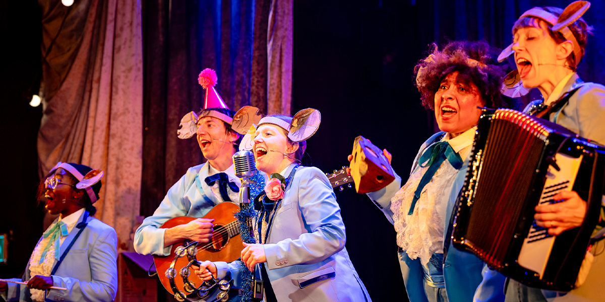A dancer in a pink tutu performs a graceful pose on stage, surrounded by festive decorations and soft lighting.
