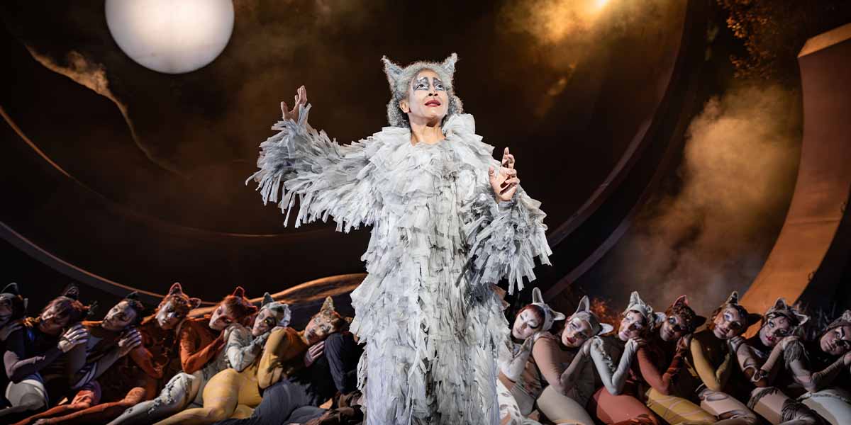 Melanie La Barrie as Old Deuteronomy performs centre stage, surrounded by cast members in cat costumes.