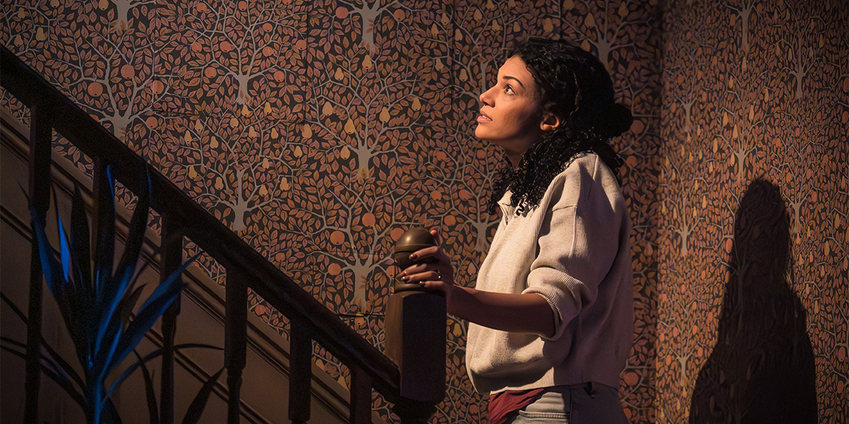 a person stands in a dimly lit room, surrounded by eerie shadows and atmospheric lighting, conveying suspense.