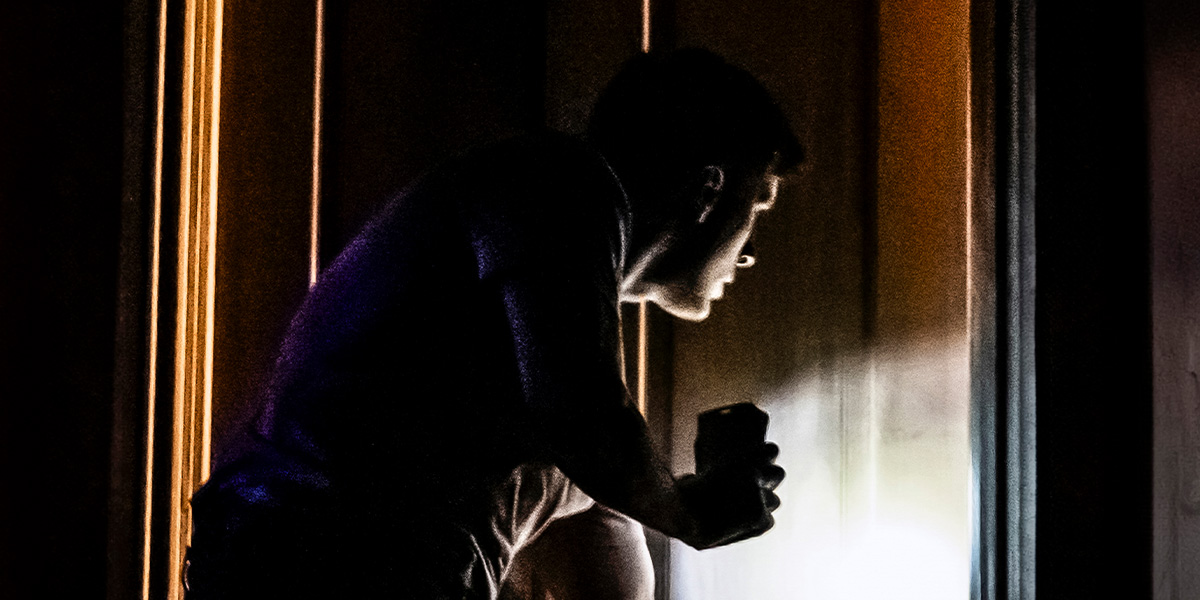 a person stands in a dimly lit room, holding a flashlight, with eerie shadows on the walls.